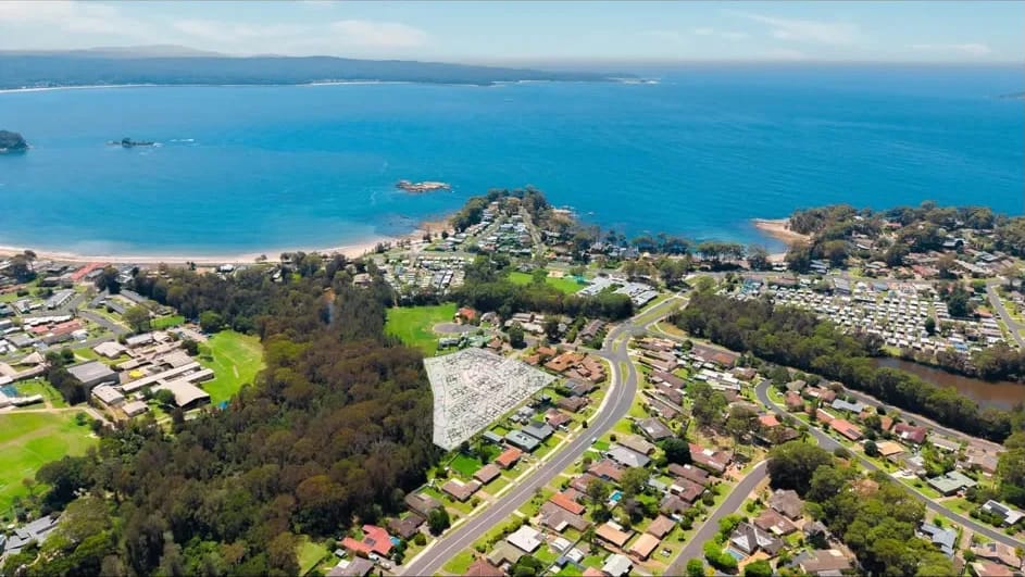 Aerial photograph of the Batemans Bay site at Sunshine Bay with the concept lot layout overlaid, looking north over the town to the bay and the ocean beyond