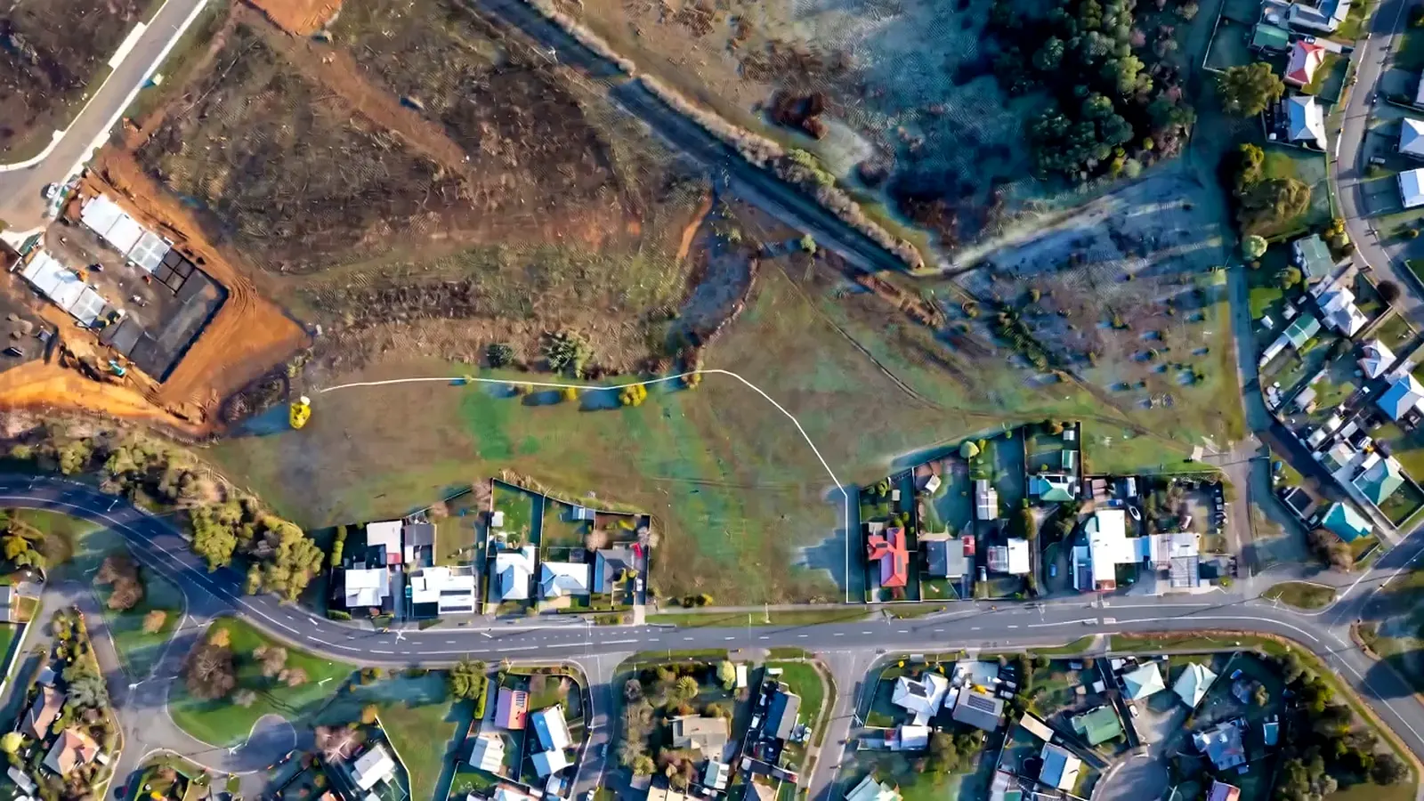 Top-down aerial of a development site with a subdivision layout drawn over it in white line work